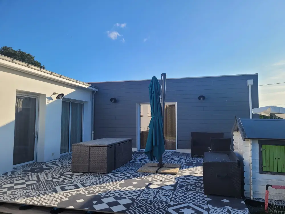 Extension en ossature bois avec bardage bois peint gris clair et toit plat